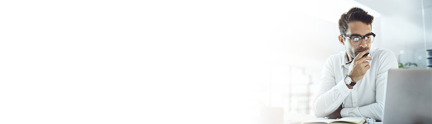 A man with glasses looks at his laptop computer.