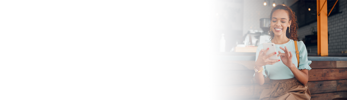 A smiling woman looks at her phone.