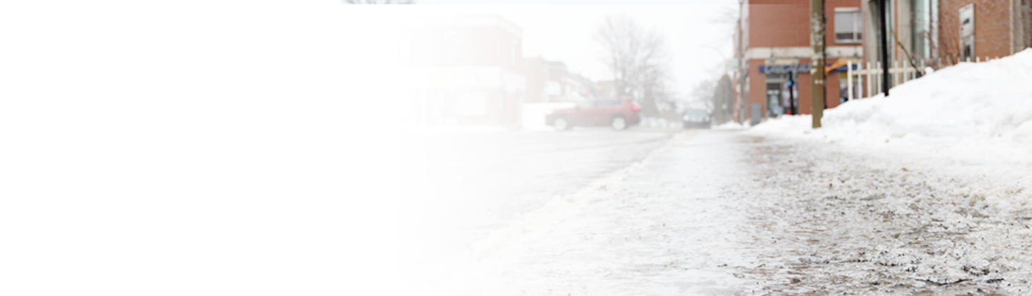 A snowy sidewalk that hasn't been shoveled.