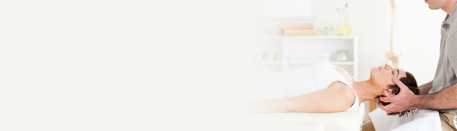 A chiropractor adjusts a patient lying on a table.