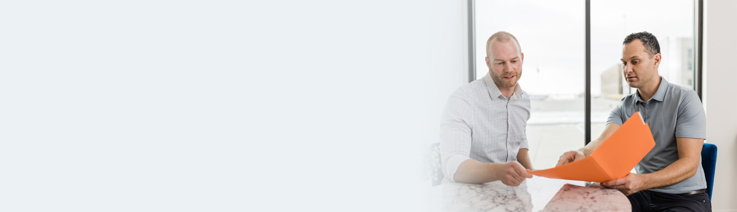 Two men talking over a file folder