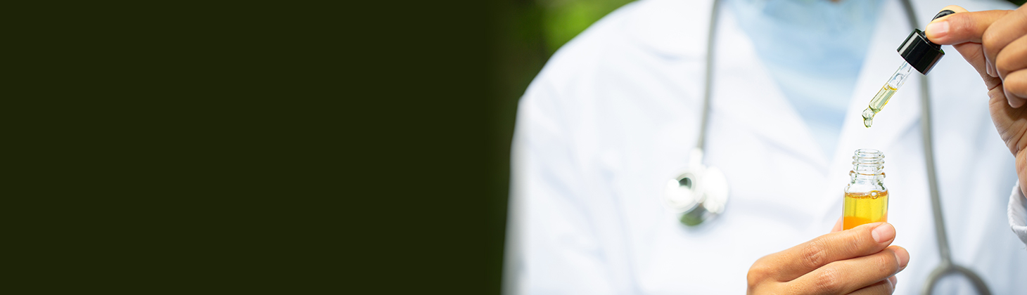 A doctor in a white coat holds a dropper of CBD oil.