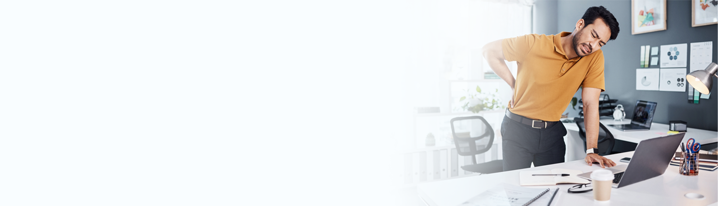 A patient winces in pain standing at a desk.